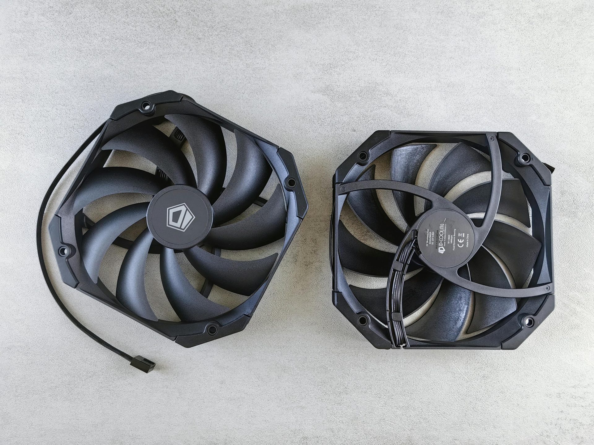 Top view of two black cooling fans on a gray concrete surface, showcasing technology equipment.